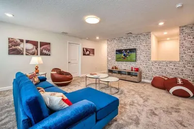 a living room with a blue couch and a tv at 6Q/6B | Piscina Privativa | Game Room Temático in Kissimmee