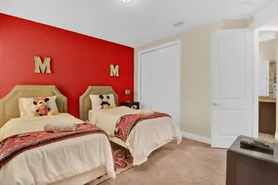two beds in a room with a red wall at Relaxing 6BR Home w Pool Near Disney in Orlando
