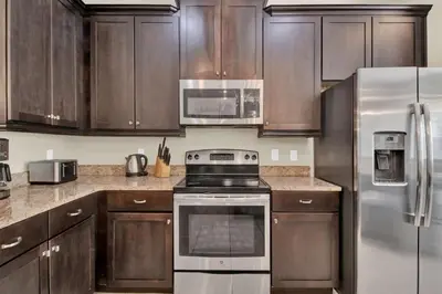 a kitchen with wooden cabinets and stainless steel appliances at Relaxing 6BR Home w Pool Near Disney in Orlando