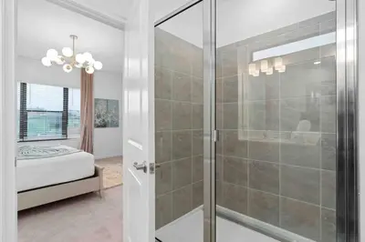 a bathroom with a shower with a glass door at SUPER RITZY - 9BDRs-9BAs w Theme Rooms LOFT & POOL in Orlando