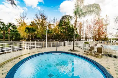 a large swimming pool with a fence and trees at Orlando 12th Floor - 5 min Disney in Orlando