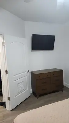 a room with a tv on a wall and a dresser at Orlando 12th Floor - 5 min Disney in Orlando