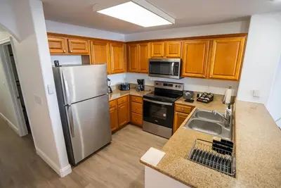 a kitchen with wooden cabinets and a stainless steel refrigerator at Orlando Blue Heron 1 Mile From Disney 2nd floor in Orlando