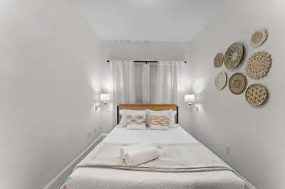 a white bedroom with a bed with white sheets and pillows at SUPER BOHO - LAKE TOHO FISHiNG CIVIC CeNTER in Kissimmee
