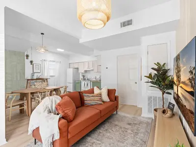a living room with a couch and a kitchen at SUPER BOHO- At LAKE TOHO's WATER SLEEPs 6 in Kissimmee