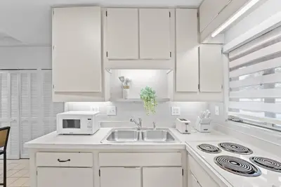 a white kitchen with a sink and a microwave at SUPER BOHO - Lake Toho Timeless Charm in Kissimmee