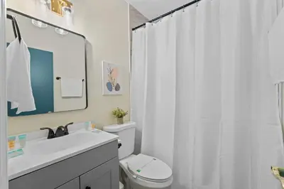 a bathroom with a white shower curtain and a toilet at SUPER BOHO - Lake Toho Timeless Charm in Kissimmee