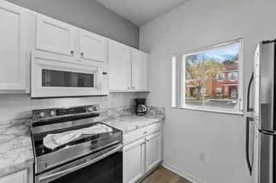 a kitchen with white cabinets and a stove and a window at SUPER YES - MANY AMENITIEs RELAX GYM COURTs in Kissimmee