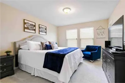 a bedroom with a large bed and a blue chair at SUPER CHIC - 4 Bedroom TOWNHOME IN DISNEY AREA in Kissimmee
