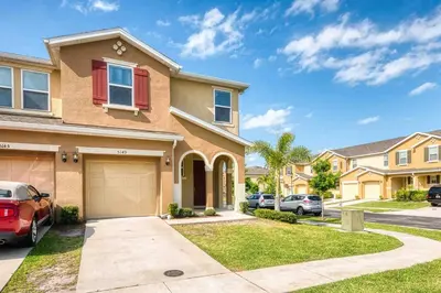 a house with cars parked in a driveway at SUPER CHIC - 4 Bedroom TOWNHOME IN DISNEY AREA in Kissimmee