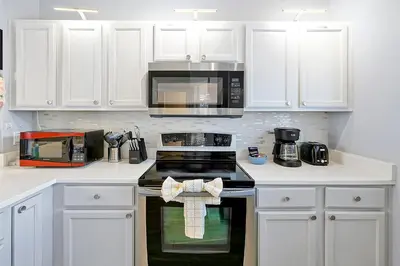 a kitchen with white cabinets and a stove top oven at Encantada Resort - Spacious 3-Bedroom Villa with Private Pool Near Disney in Kissimmee