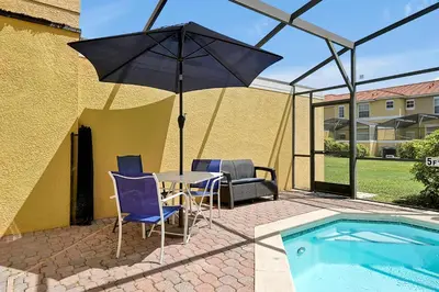 a patio with a table and an umbrella next to a pool at Encantada Resort - Spacious 3-Bedroom Villa with Private Pool Near Disney in Kissimmee
