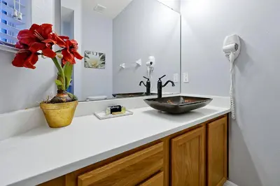 a bathroom with a sink and a vase with red flowers at Encantada Resort - Spacious 3-Bedroom Villa with Private Pool Near Disney in Kissimmee
