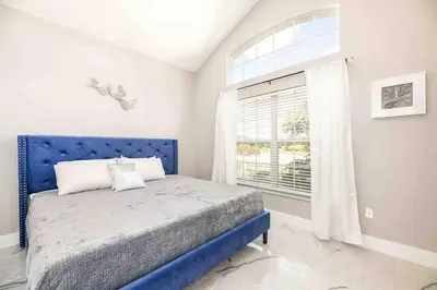 a blue bed in a white room with a window at SUPER GLAM - GAME ROOM and POOL in Orlando