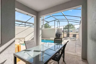a dining room with a glass table on a patio at SUPER DOPE- Home w POOL & AMENITIEs in Kissimmee