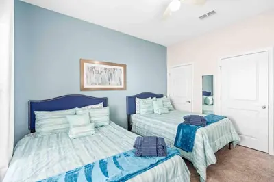 two beds in a bedroom with blue walls at SUPER DOPE- Home w POOL & AMENITIEs in Kissimmee