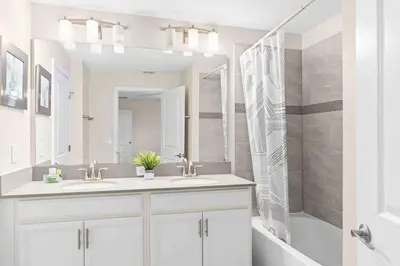 a bathroom with two sinks and a shower and a tub at SUPER DOPE- Home w POOL & AMENITIEs in Kissimmee