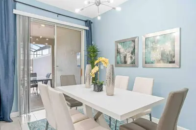 a dining room with a white table and chairs at SUPER DOPE- Home w POOL & AMENITIEs in Kissimmee