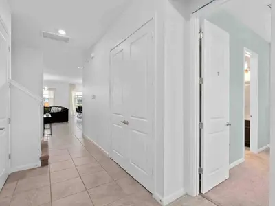 a hallway with white doors and a living room at SUPER JUMBO - 12BD 12BAs SLEEPs 34 - w AMENITIEs in Kissimmee