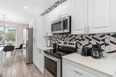 a kitchen with a stove and a microwave at SUPER EPIC- SLEEPs 32 TWO Separate Townhomes in Kissimmee