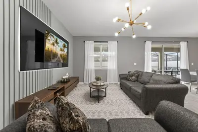 a living room with a couch and a tv at SUPER BLISS - 9BDR SLEEPs 30 - MOVIE ROOM & POOL in Kissimmee