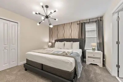 a bedroom with a large bed and a chandelier at SUPER BLISS - 9BDR SLEEPs 30 - MOVIE ROOM & POOL in Kissimmee