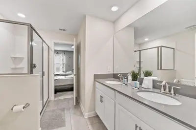 a bathroom with two sinks and a shower at SUPER BLISS - 9BDR SLEEPs 30 - MOVIE ROOM & POOL in Kissimmee