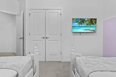 a white bedroom with two beds and a painting on the wall at SUPER GIANT - 12BD 12BAs - SLEEP 38 & NEAR DiSNEY in Kissimmee