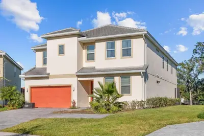 a large white house with a red garage at SUPER GIANT - 12BD 12BAs - SLEEP 38 & NEAR DiSNEY in Kissimmee