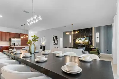 a dining room with a long table and white chairs at SUPER GIANT - 12BD 12BAs - SLEEP 38 & NEAR DiSNEY in Kissimmee