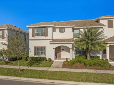a large white house with a palm tree at Super Chill - 5 Bedrooms WPOOls in Kissimmee