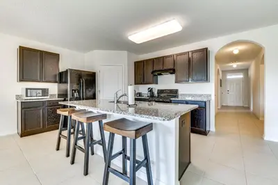 a kitchen with a large island with bar stools at 7 Mi to USTA Waterfront Tennis House with Yard! in Kissimmee