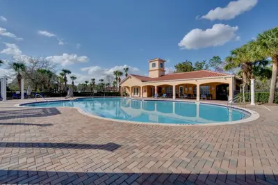 a swimming pool with a building in the background at 7 Mi to USTA Waterfront Tennis House with Yard! in Kissimmee