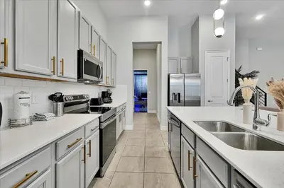 a kitchen with white cabinets and stainless steel appliances at Gorgeous Paradiso Mansion Pool-Game-Room-Theater-3 in Orlando