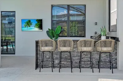 a table with four rattan chairs in front of a building at Gorgeous Paradiso Mansion Pool-Game-Room-Theater-3 in Orlando
