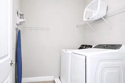 a white laundry room with a washer and dryer at Home With Splash Pad And Slide, Movie Theater & Game Room With Waterpark & Resort Access - 417Sf in Kissimmee