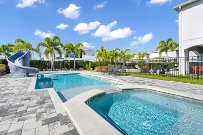 a swimming pool with a slide next to a house at Home With Splash Pad And Slide, Movie Theater & Game Room With Waterpark & Resort Access - 417Sf in Kissimmee