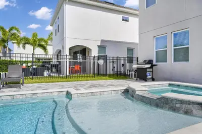 a swimming pool in front of a house with a piano at Home With Splash Pad And Slide, Movie Theater & Game Room With Waterpark & Resort Access - 417Sf in Kissimmee