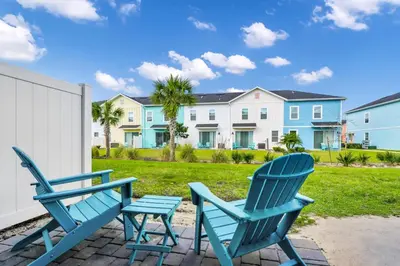 two blue chairs sitting on a patio in front of a house at Comfy Villa Near Disney With Margaritaville Resort & Island H20 Access - 8155Cp in Orlando