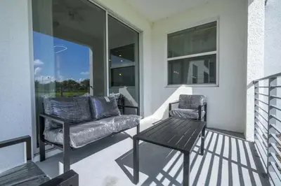 a porch with a couch and a chair and a table at Apto 2Q Vista Lago | 10 min Disney in Kissimmee