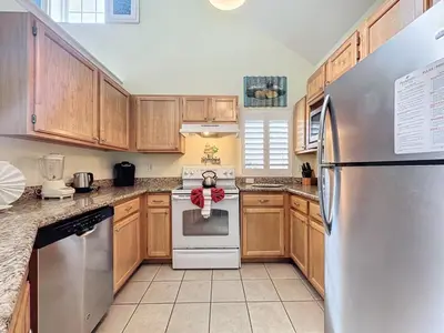 a kitchen with wooden cabinets and a stainless steel refrigerator at Two Bedroom Condo near Disney condo in Kissimmee