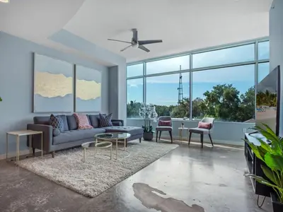 a living room with a couch and chairs and large windows at Luxurious 2 Beds 2 Baths Downtown Apartment in Orlando