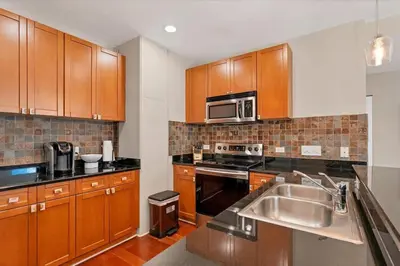 a kitchen with wooden cabinets and a stainless steel sink at Beautiful Downtown Condo 1 Bed 1 Bath in Orlando
