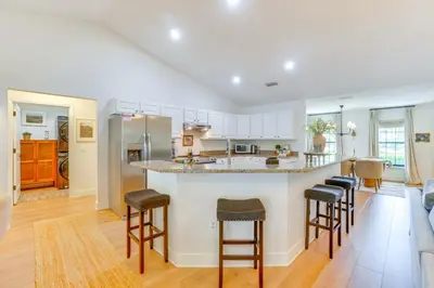 a kitchen and living room with a counter and stools at Near Parks and Lakes Sorrento Home with Pool and Yard! in Sorrento