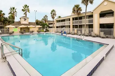 a large swimming pool at a hotel with palm trees at Modern- 2 Queen bed suite with pool near Disney World in Kissimmee