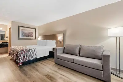 a hotel room with a bed and a couch at Red Roof Inn Kissimmee, FL in Kissimmee