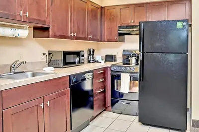 a kitchen with wooden cabinets and a black refrigerator at King Suite w BBQ & Games Room - Sand Lake in Orlando