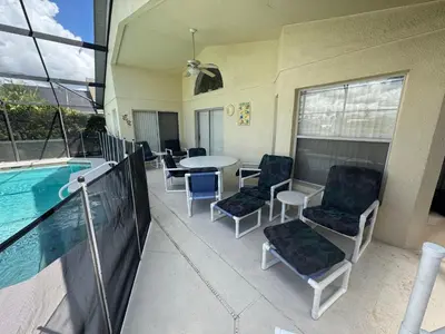 a patio with a table and chairs next to a pool at Sunset Villa – Your Gateway to a Magical Florida Vacation! in Kissimmee