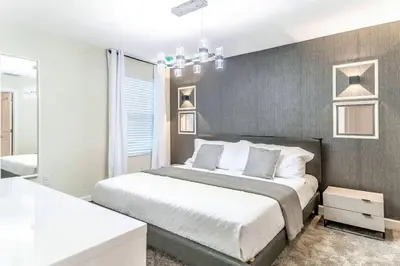 a bedroom with a large bed and a bathroom at FLASH SALE Pvt Pool and Spa Home at Storey Lake in Kissimmee
