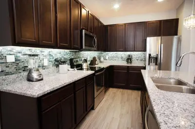 a kitchen with wooden cabinets and marble counter tops at Flash 20 Off Gorgeous Vacation Home near Everywhere in Kissimmee